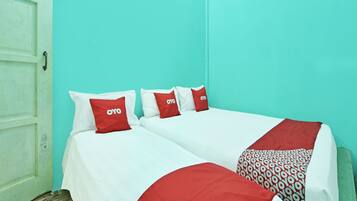 A room with two beds, each with white bedding and red pillows with the 'OYO' logo.