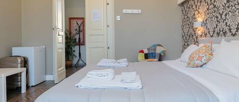 Une chambre d’hôtel avec un lit bien fait, un bureau avec une chaise, une petite table et une valise.