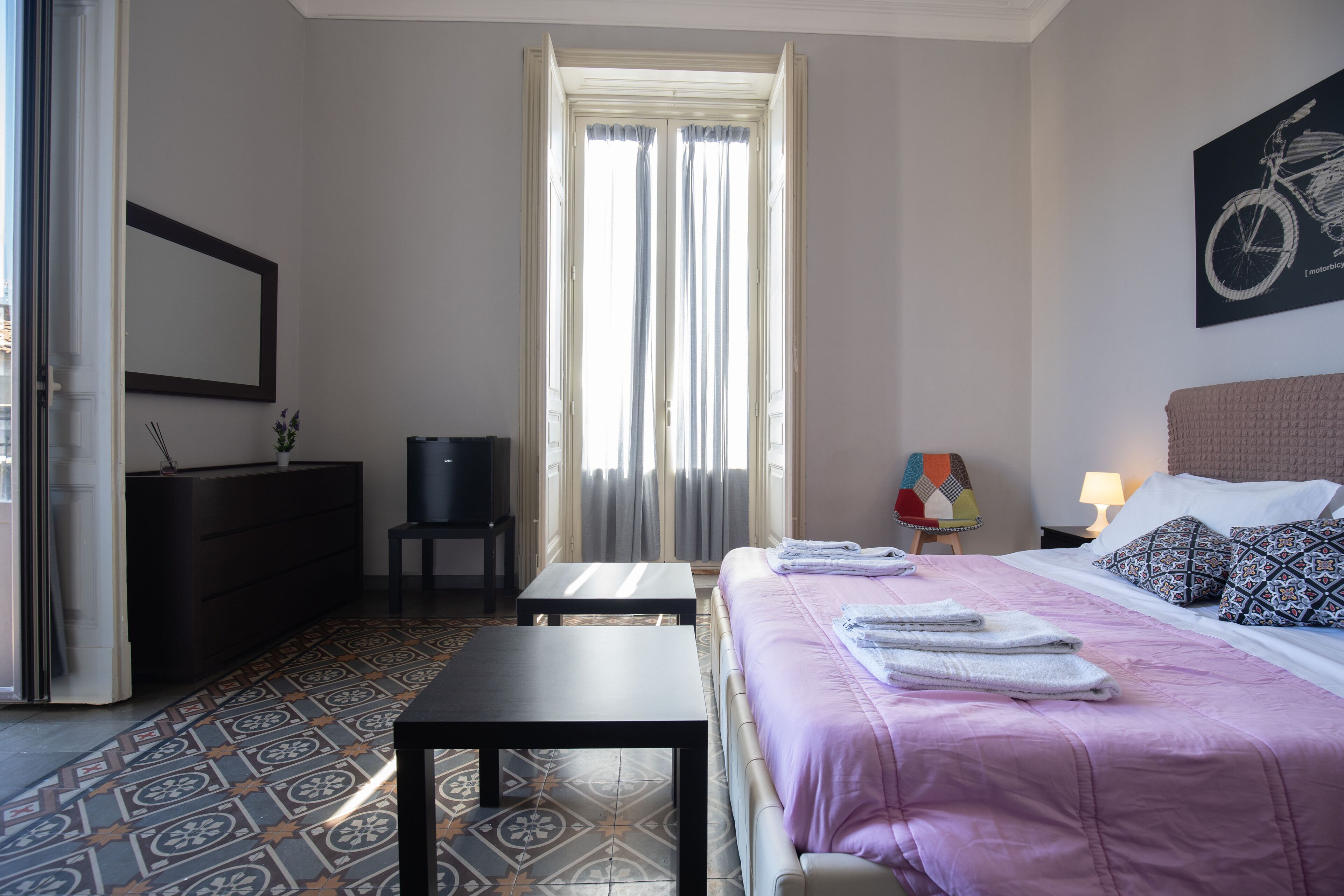 A hotel room with a bed, a desk, a chair, a TV, and a window with curtains.
