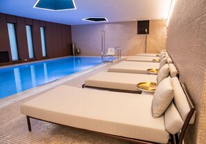 Una piscina techada, sillones reclinables de piscina
