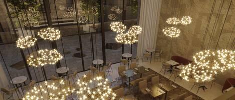 A modern interior with tables and chairs arranged for dining, large windows, and decorative hanging lights.