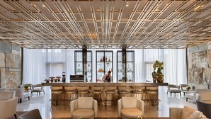 A modern bar area with a bartender, bar stools, and a display of bottles. - Theatron Jerusalem Hotel & Spa - MGallery Collection (Jerusalem)