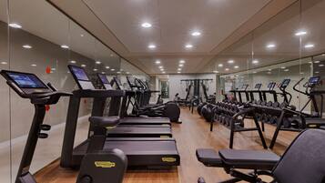 Une salle de sport équipée de tapis de course, de vélos elliptiques et de bancs de musculation.