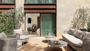 An outdoor seating area with a sofa, chairs, and a small table with a fruit bowl. - Theatron Jerusalem Hotel & Spa - MGallery Collection (Jerusalem)
