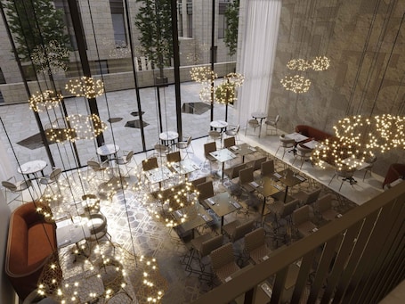 A modern hotel lobby with glass walls, multiple seating areas, and decorative lighting.. Theatron Jerusalem Hotel & Spa - MGallery Collection