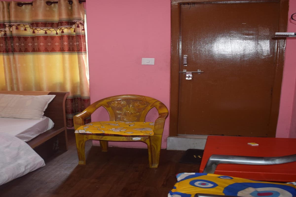 Une chambre à coucher avec un lit, une chaise en bois, une table rouge et une porte.