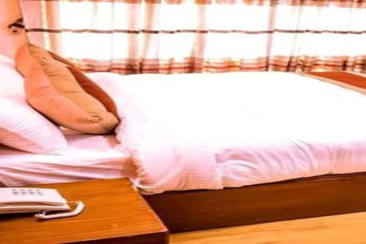 Une chambre à coucher avec un lit en bois, une literie blanche, un seul oreiller et une table de chevet avec un téléphone.