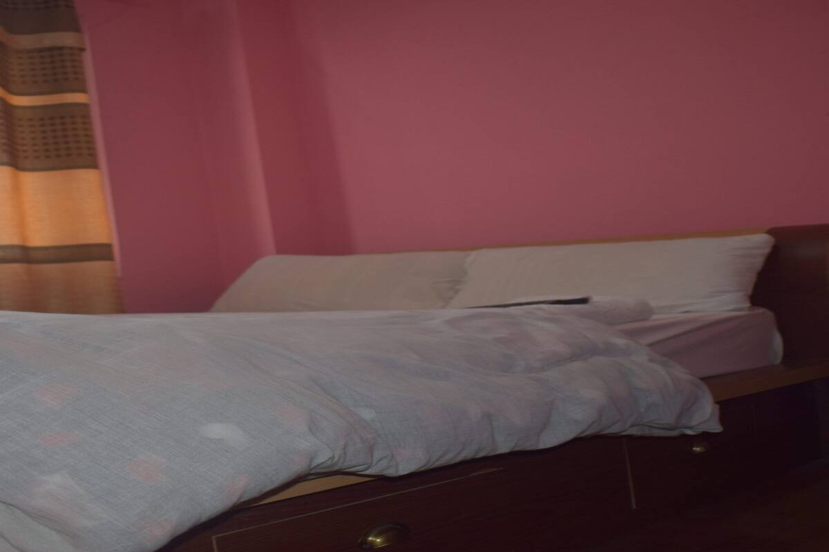 Une chambre à coucher avec un lit, des oreillers, une tête de lit en bois et un rideau.