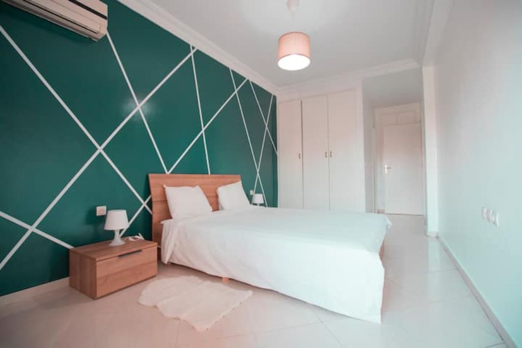 A bedroom with a bed, nightstand, and wall-mounted air conditioning unit.