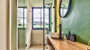 A modern bathroom with a glass shower enclosure, a wooden vanity, and a large mirror. - The Harri 209 (Cape Town)