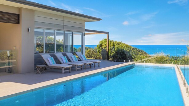A modern poolside area with lounge chairs and a view of the ocean.