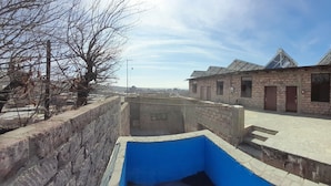Une cour avec un bâtiment en briques, un élément décoratif aquatique bleu et un ciel dégagé.