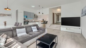 A modern living room with a grey sofa, a black coffee table, and a flat-screen TV mounted on the wall. - Apartment 2217/65764 (Istria - Medulin), 1200m from the beach (Medulin)