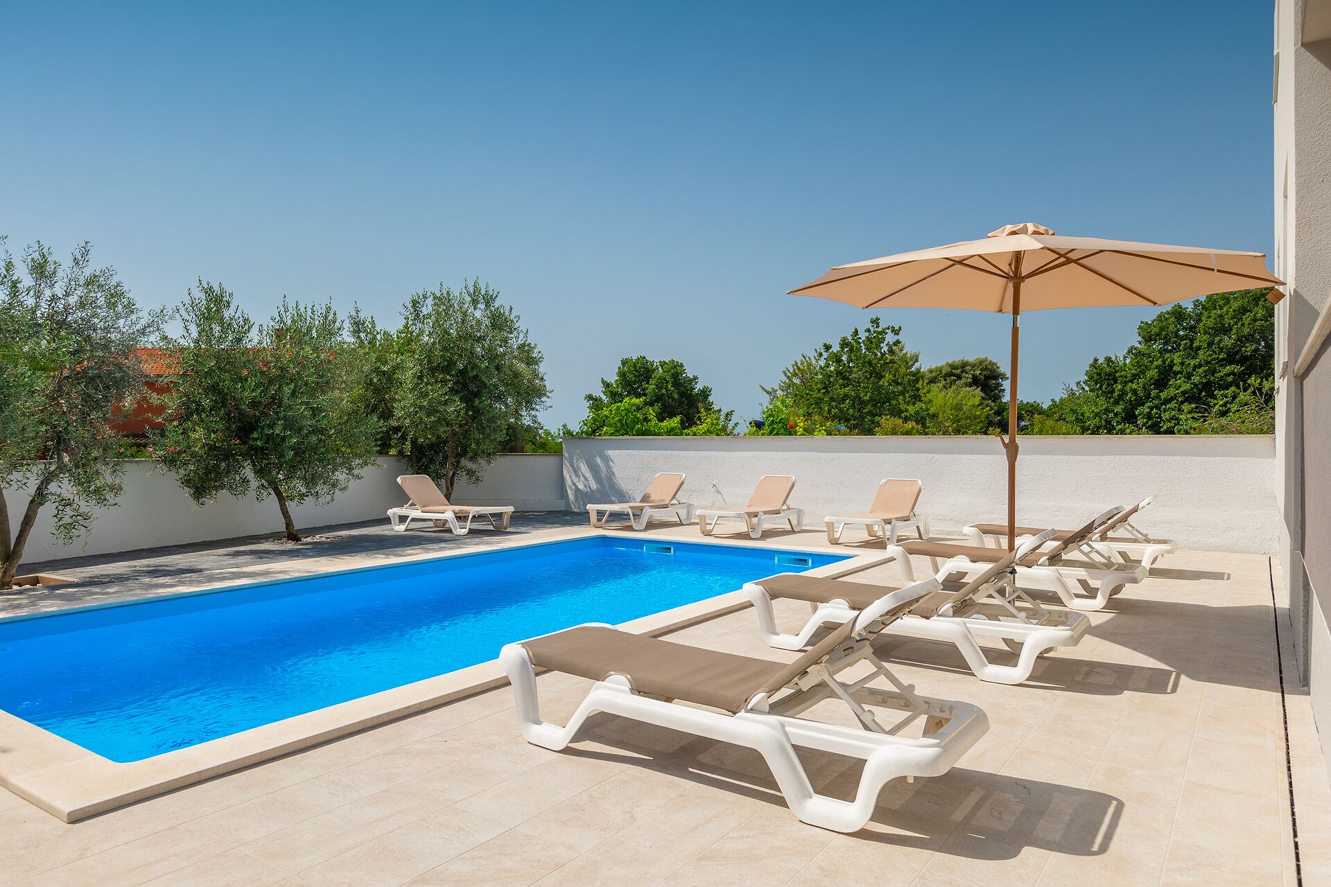 A swimming pool with lounge chairs and an umbrella.