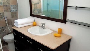 Une salle de bain avec un lavabo blanc, un miroir et une serviette.