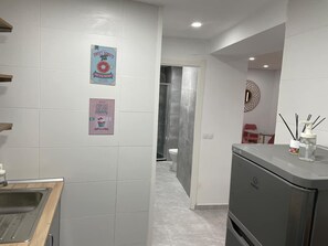 Et moderne badeværelse med bruser, toilet og et vaskebord med spejl og toiletartikler.
