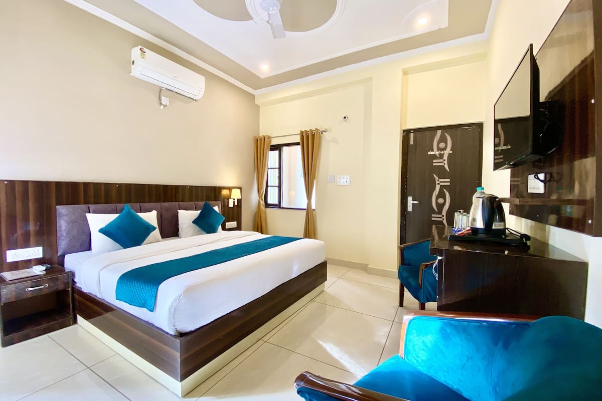 A hotel room with a large bed, a desk with a chair, a flat-screen TV, and a ceiling fan.