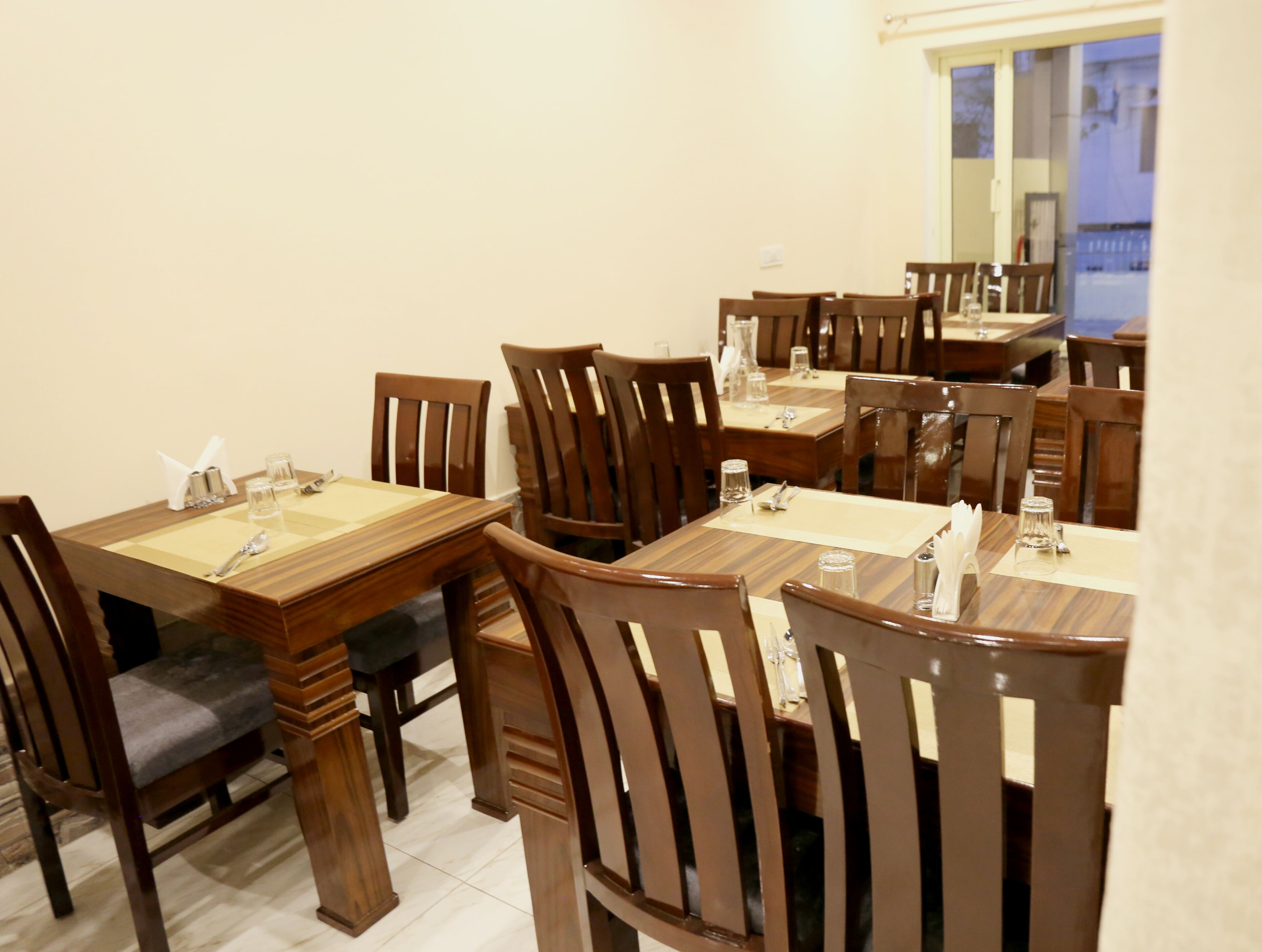 A dining area with wooden tables and chairs, arranged in a spacious layout.
