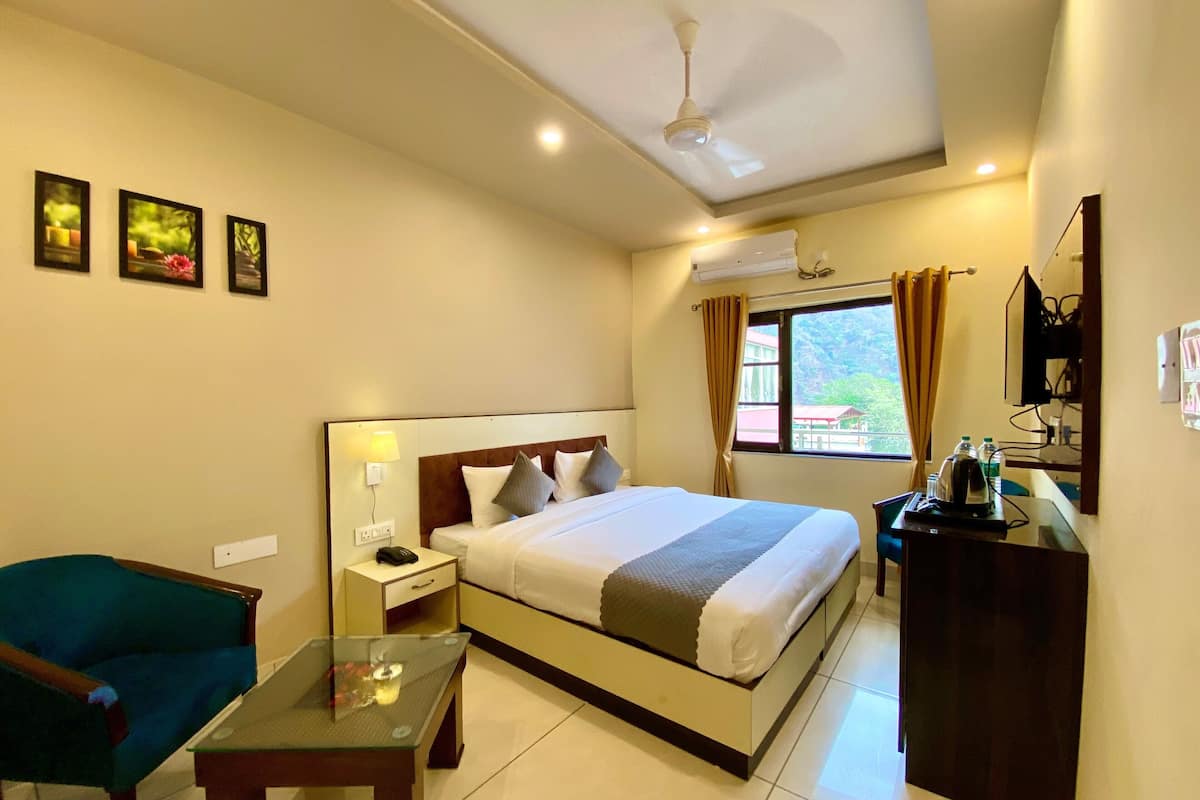 A hotel room with a bed, a desk, a chair, a nightstand, and a ceiling fan.