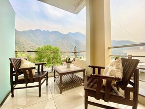 A balcony with two wooden chairs, a small table, and a potted plant. - Tapovan New Residency (5 minutes walk to Laxman jhula) (Narendranagar)