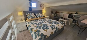 Une chambre à coucher avec un lit, des tables de chevet, un bureau et une chaise.