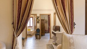 A room with a bed, a desk with a computer, and a chair. There is a window with curtains, a radiator, and a rug on the floor. - Villa a Montaione ID 3114 (Montaione)