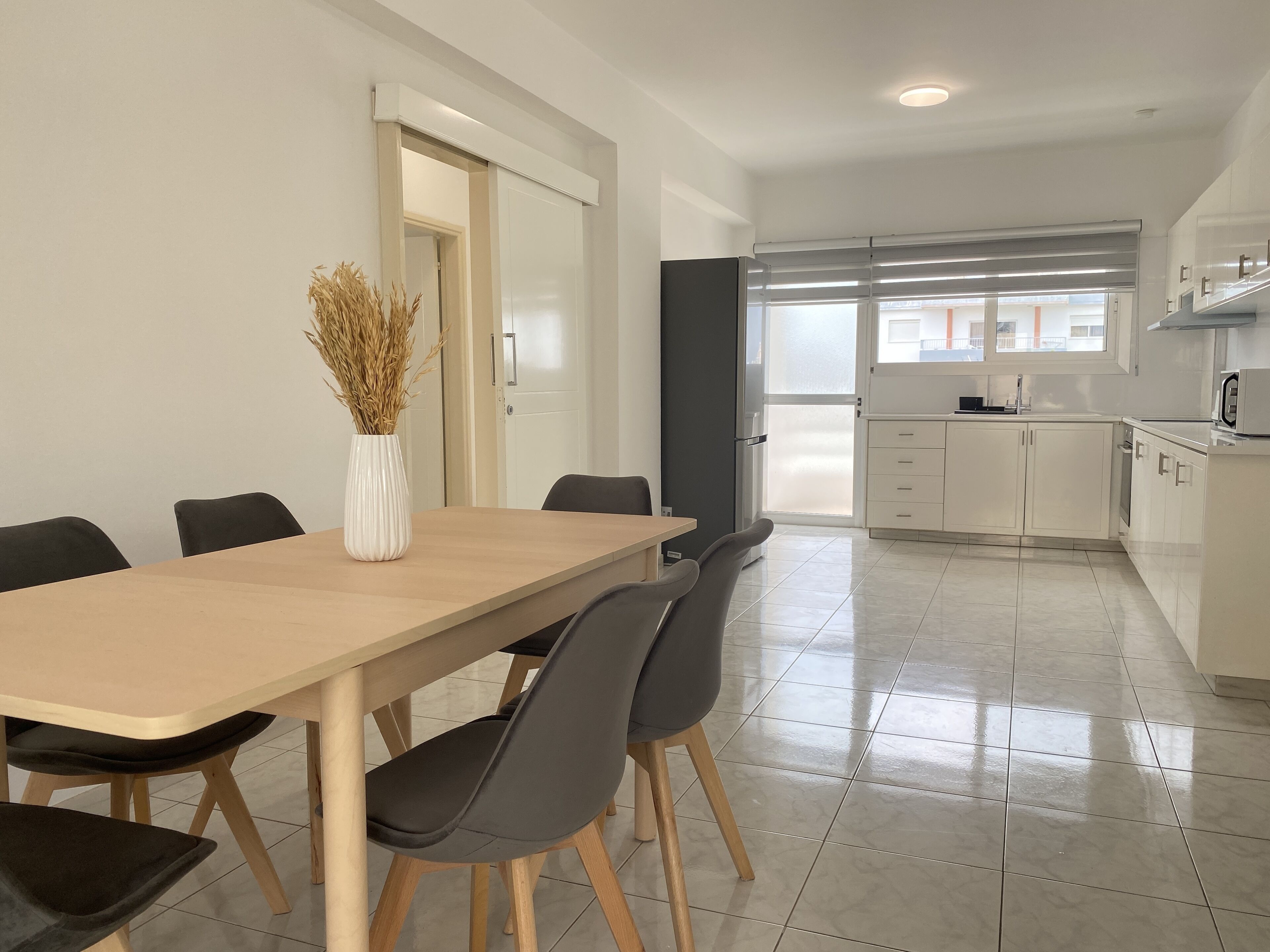 A modern kitchen with white cabinets, a built-in oven, and a microwave.