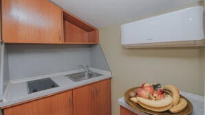 Eine Küche mit Holzausstattung, einer Arbeitsplatte aus Granit, einer Spüle aus Edelstahl und einer weißen Wand-Klimaanlage.