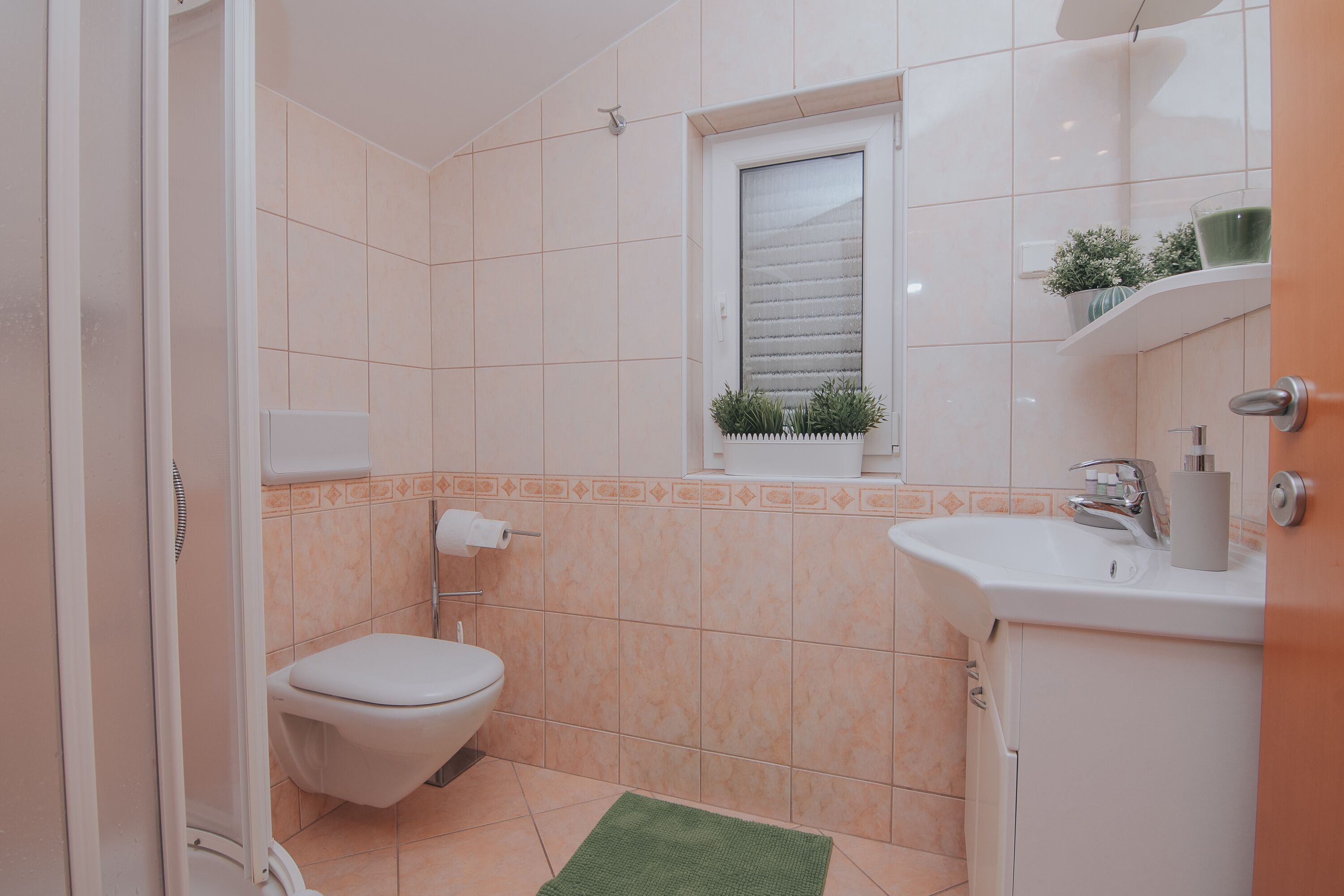 A bathroom with a toilet, sink, and window.