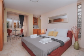 A hotel room with a bed, a small dining area, and a kitchenette.