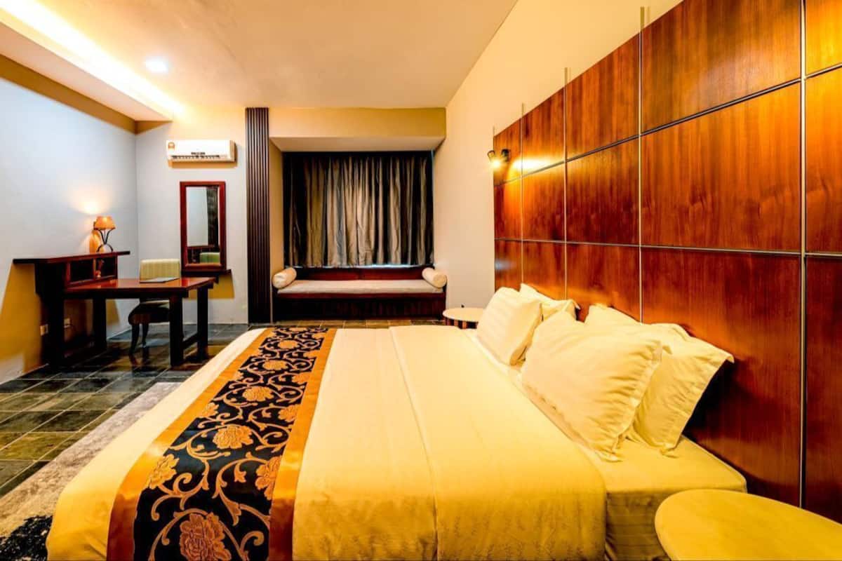 Una habitación de hotel con cama, escritorio, silla, espejo y armario.