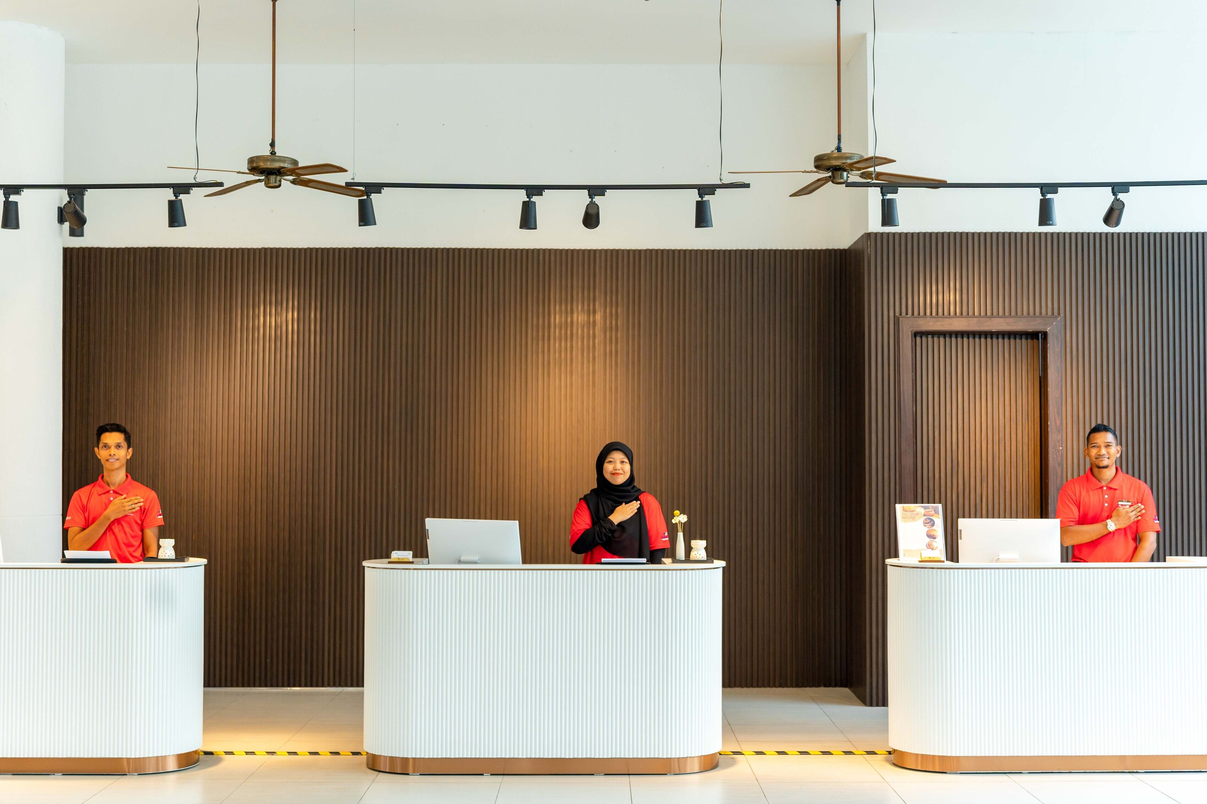 Three reception desks in a modern lobby with ceiling fans and recessed lighting.