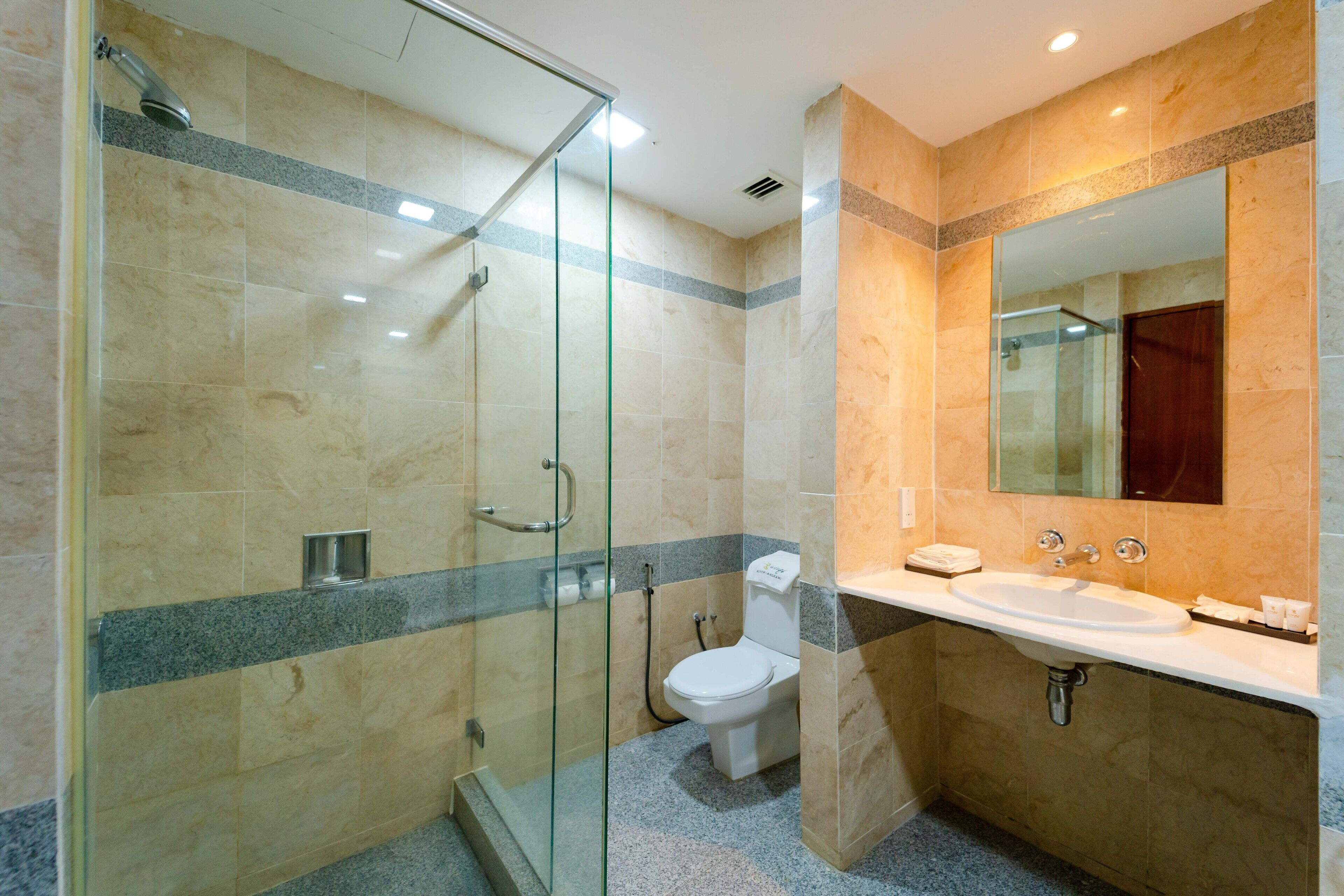 Een moderne badkamer met een douchecabine van glas, een wit toilet en een wastafel met spiegel erboven.