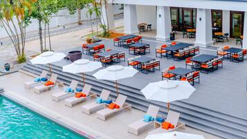 Area piscina con lettini e tavoli, una zona relax coperta e una piscina.