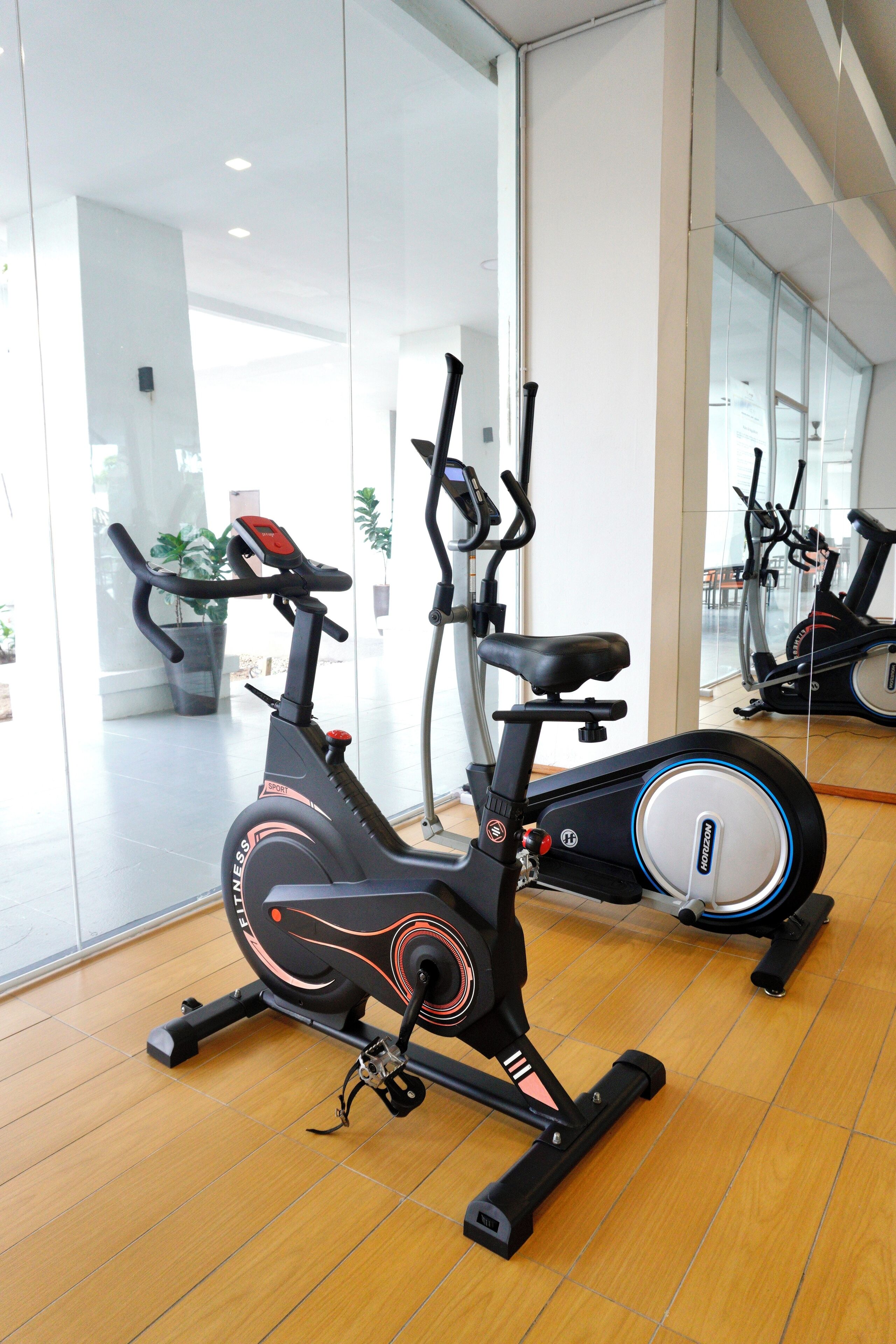 An exercise bike in a gym with a wooden floor and glass walls.