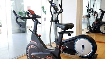 An exercise bike in a gym with a wooden floor and glass walls.