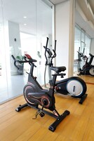 Una bicicleta estática en un gimnasio con suelo de madera y paredes de vidrio.