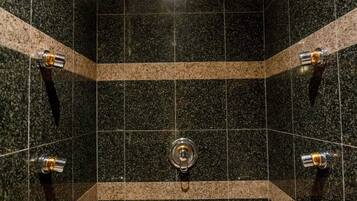 Un bagno moderno con piastrelle in granito scuro, un lavandino centrale e una vasca da bagno a semicircolo.