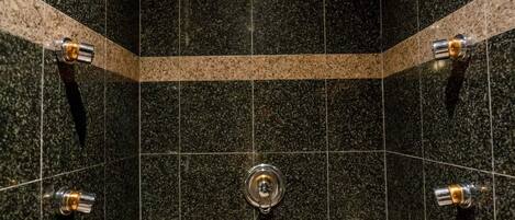 A modern bathroom with dark granite tiles, a central sink, and a curved bathtub.