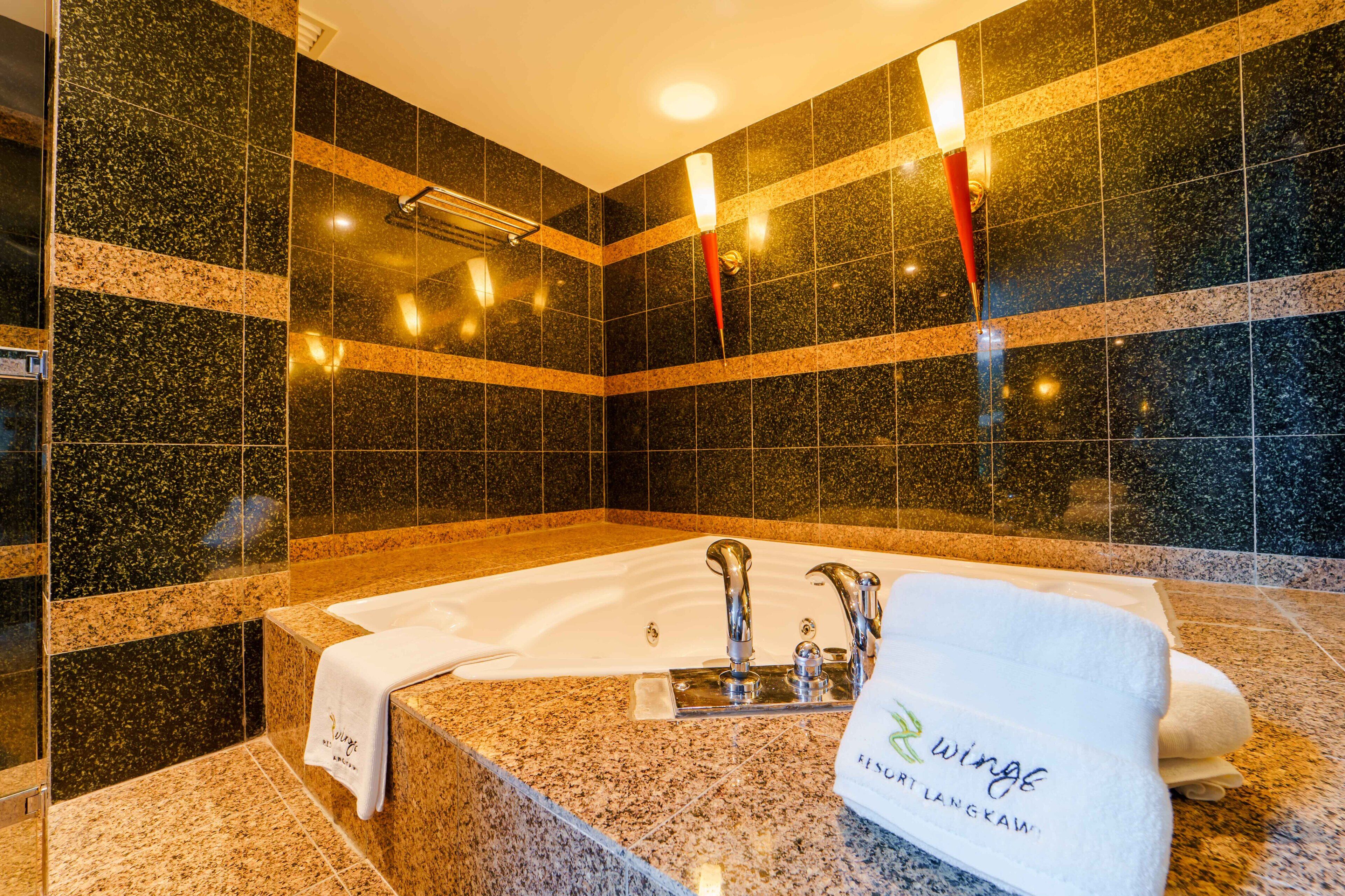 A modern bathroom with a large bathtub, granite tiles, and a towel with 'Wing' branding.