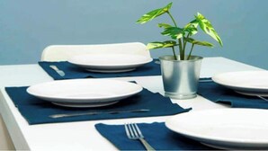 Et spisebord dækket med tallerkener, bestik og en potteplante.
