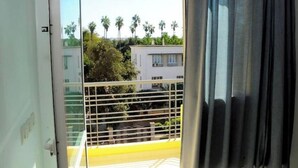 En balkon med udsigt til palmer og bygninger.