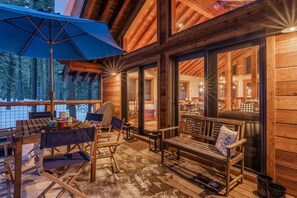 Relax on the deck with a view of the surrounding forest, surrounded by a seating area with a table and chairs.