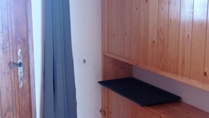 Une porte en bois avec une poignée en métal, un rideau bleu et une étagère en bois avec une tablette noire.
