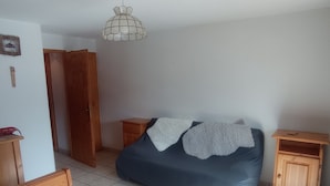 Une chambre à coucher avec un lit, des tables de chevet en bois, un banc en bois, un sol carrelé et un luminaire suspendu.
