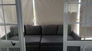 Una habitación con un sofá gris, una ventana con vistas y un techo blanco.