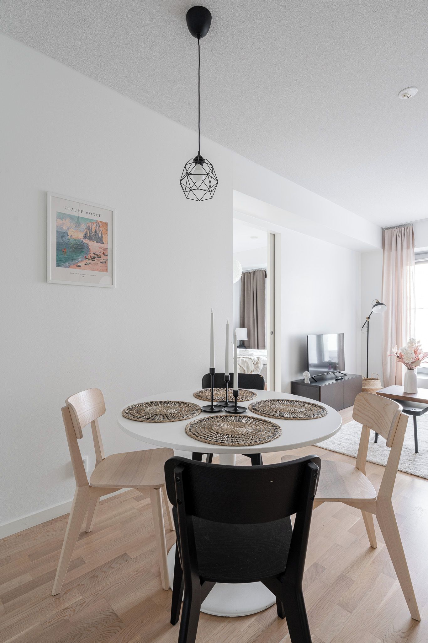 A modern dining area with a round table, chairs, and a pendant light.