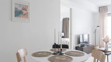 A modern dining area with a round table, chairs, and a pendant light.