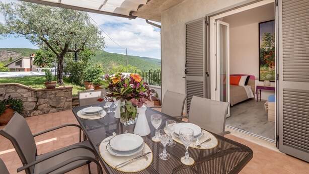 A dining area with a table set for four, a vase with flowers, and a view of a mountain landscape. - Lovely home in Amelia with kitchen (Amelia)