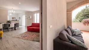 A spacious living area with a red sofa, a wicker sofa, and a dining area with a chandelier. - Lovely home in Amelia with kitchen (Amelia)